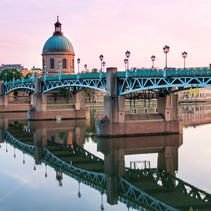 Vue sur le dôme de la Grave et le pont Saint-Pierre à Toulouse au coucher du soleil.